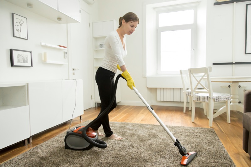 woman casual wear vacuum cleaning carpet